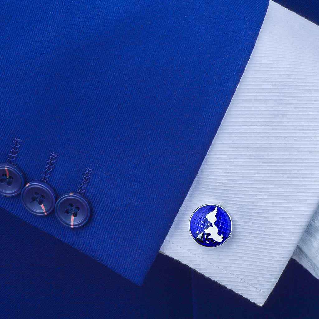Blue world map cufflink on a white shirt cuff with silver fastening