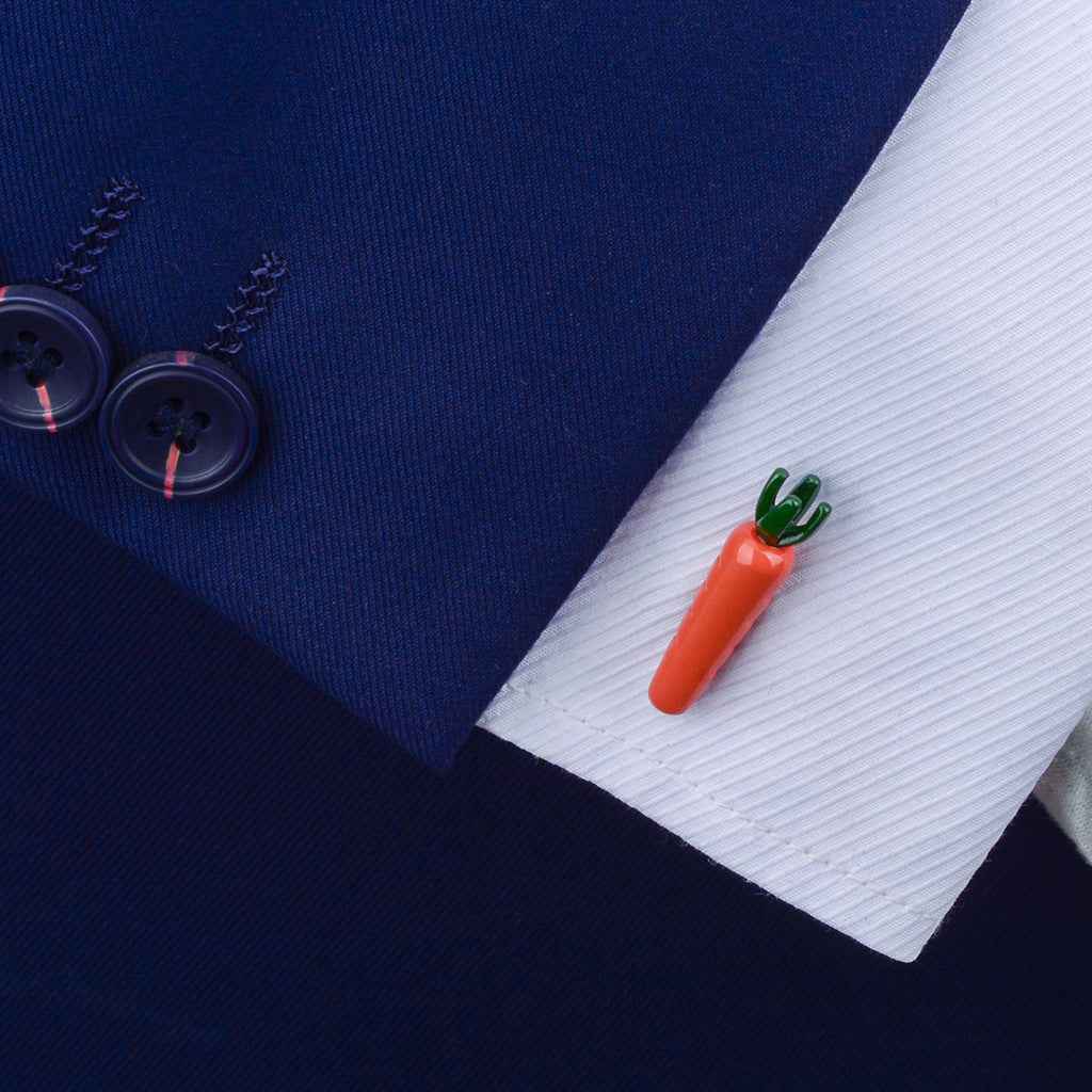 Carrot-shaped cufflinks fastened on a white dress shirt cuff; red carrot with green leaves