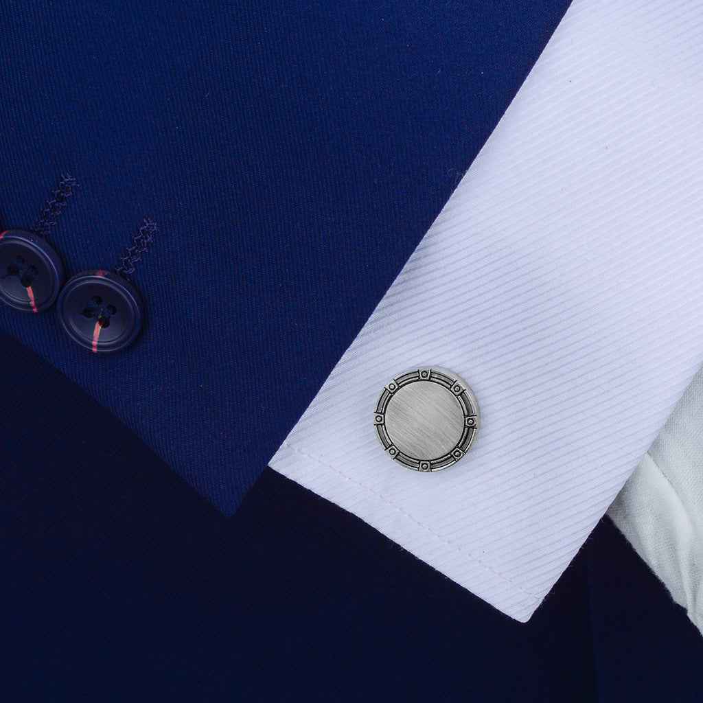 Round antique silver cufflink on a dress shirt cuff, brushed face and segmented ring