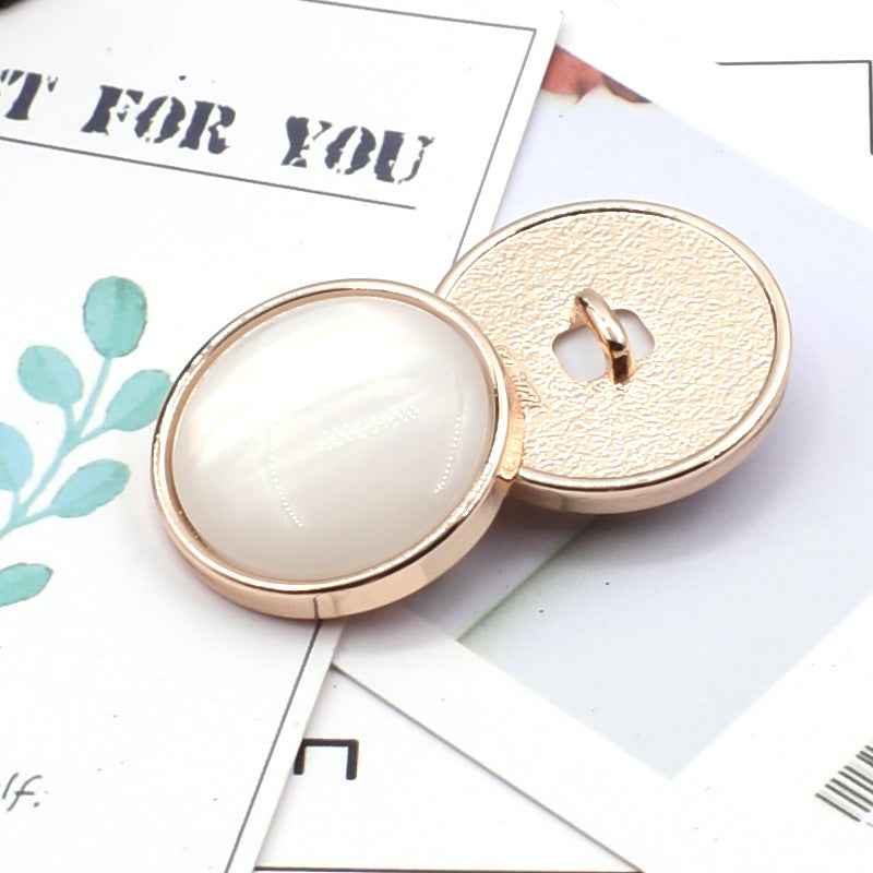 Cat-eye resin coat button: white oval front with gold metal shank and textured back.