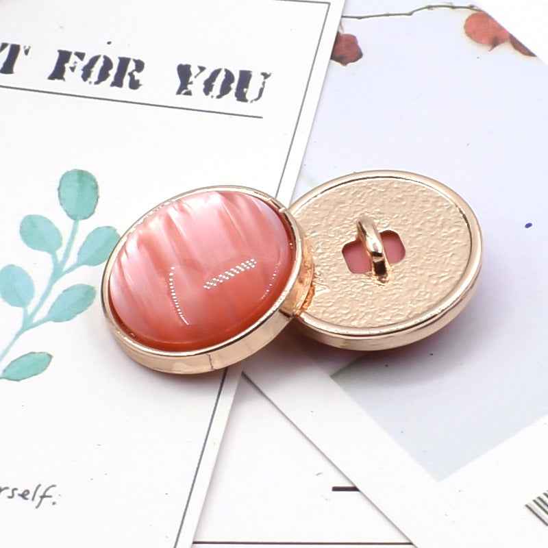 Cat-eye resin coat button: pink oval front with gold metal shank and textured back.