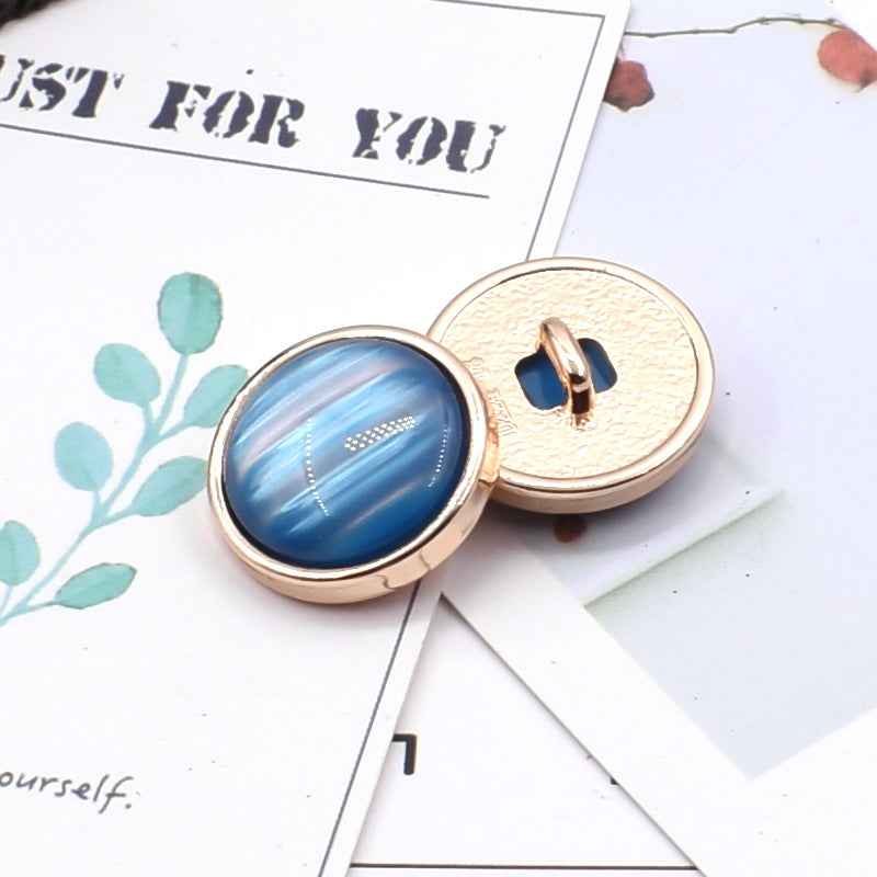 Cat-eye resin coat button: blue oval front with gold metal shank and textured back.