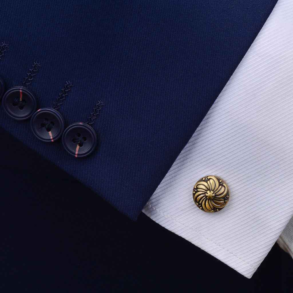 Round antique bronze cufflink on dress shirt cuff, engraved floral pattern