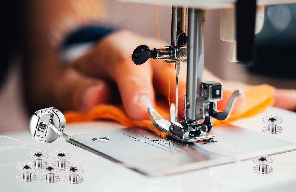 Metal bobbins on white fabric near sewing machine needle and presser foot