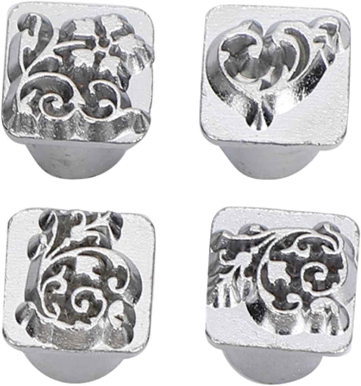 Four ornate metal stamp heads: swirls, flowers, and geometric detailing