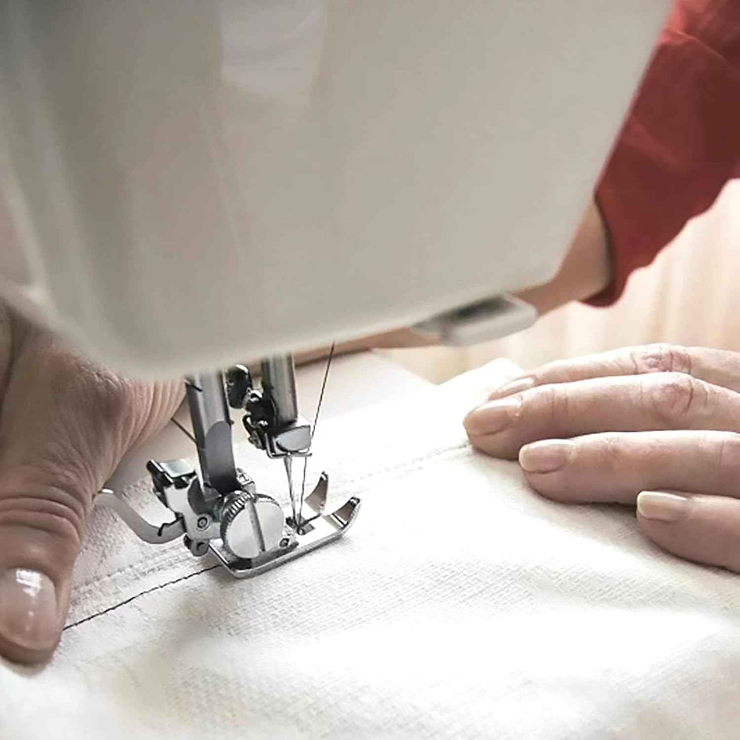 Hands sewing with straight-stitch presser foot on white fabric