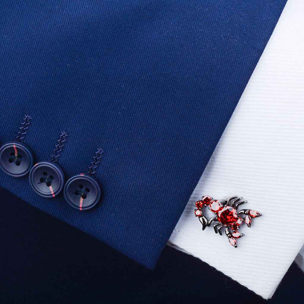 Red scorpion cufflink fastened on shirt cuff with dark metal claws