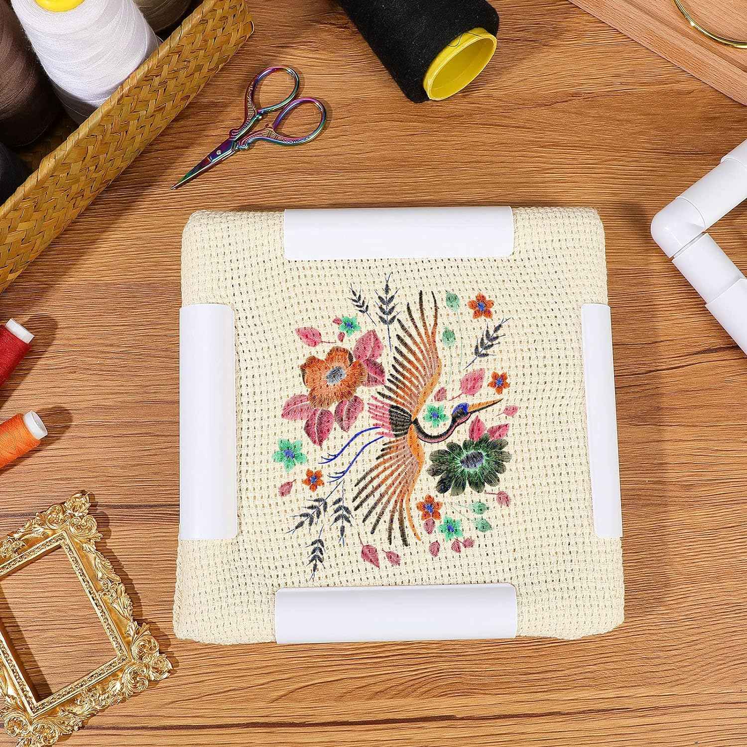 White embroidery hoop frame holding a floral cross-stitch fabric panel