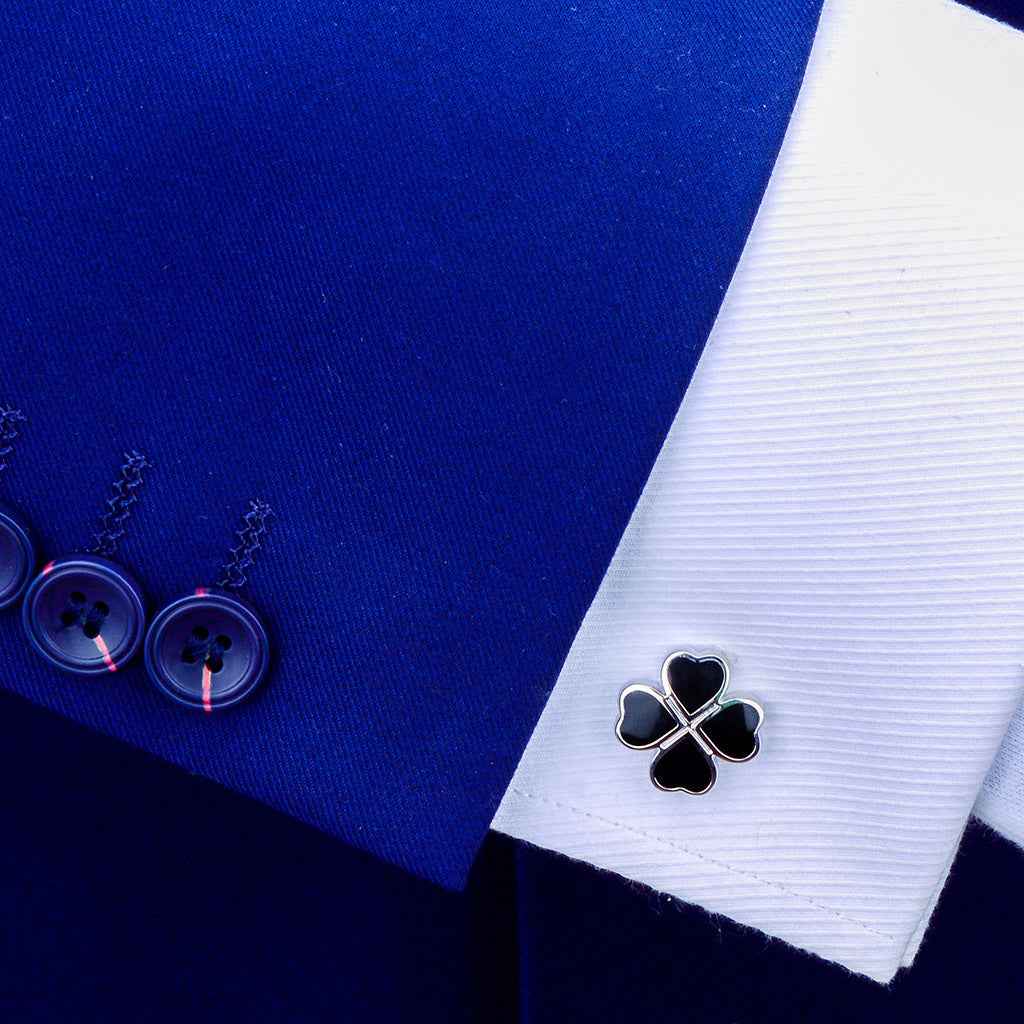Black enamel four-leaf clover cufflink on a white shirt cuff