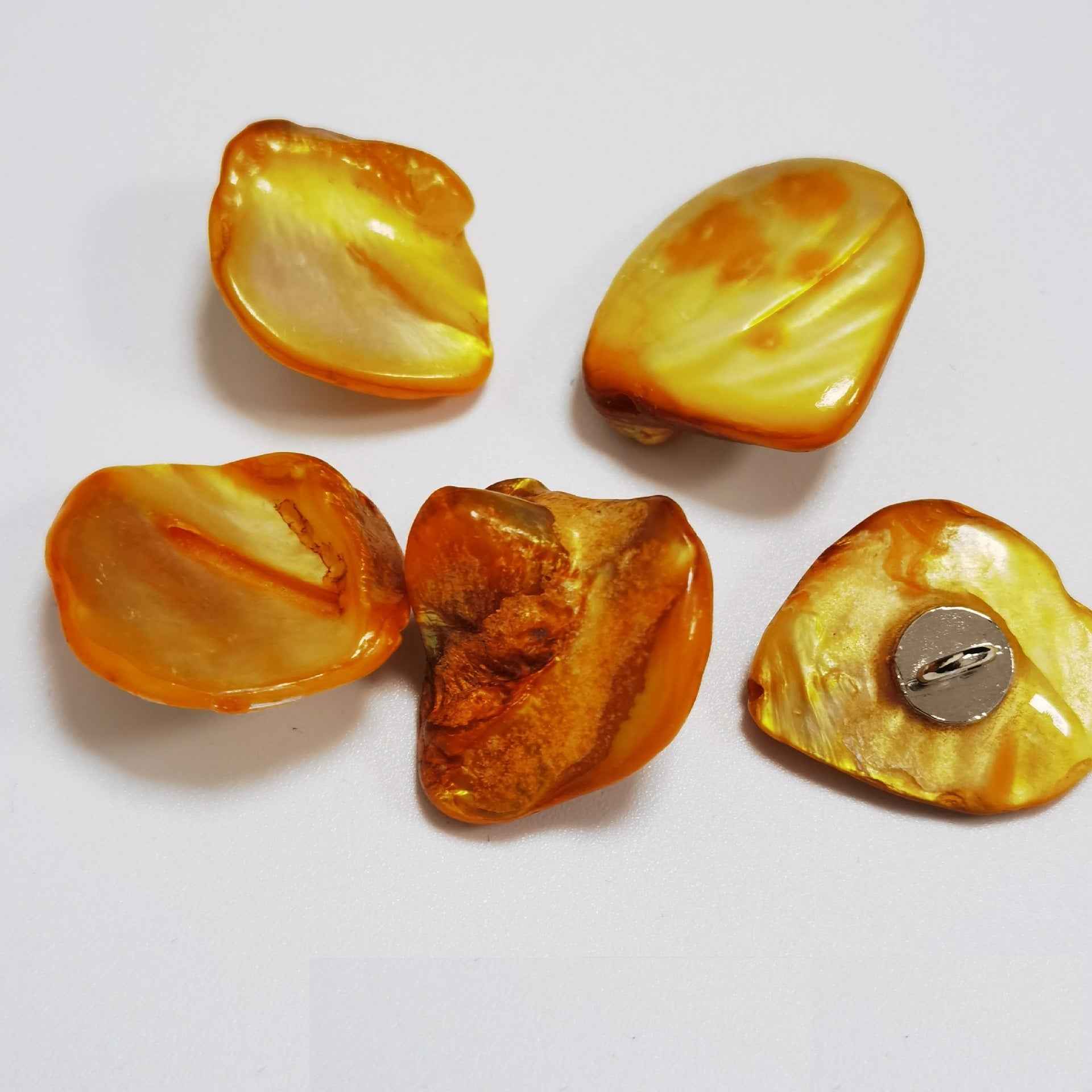 Yellow-orange irregular shell shank buttons with metal loop shanks, glossy surface.