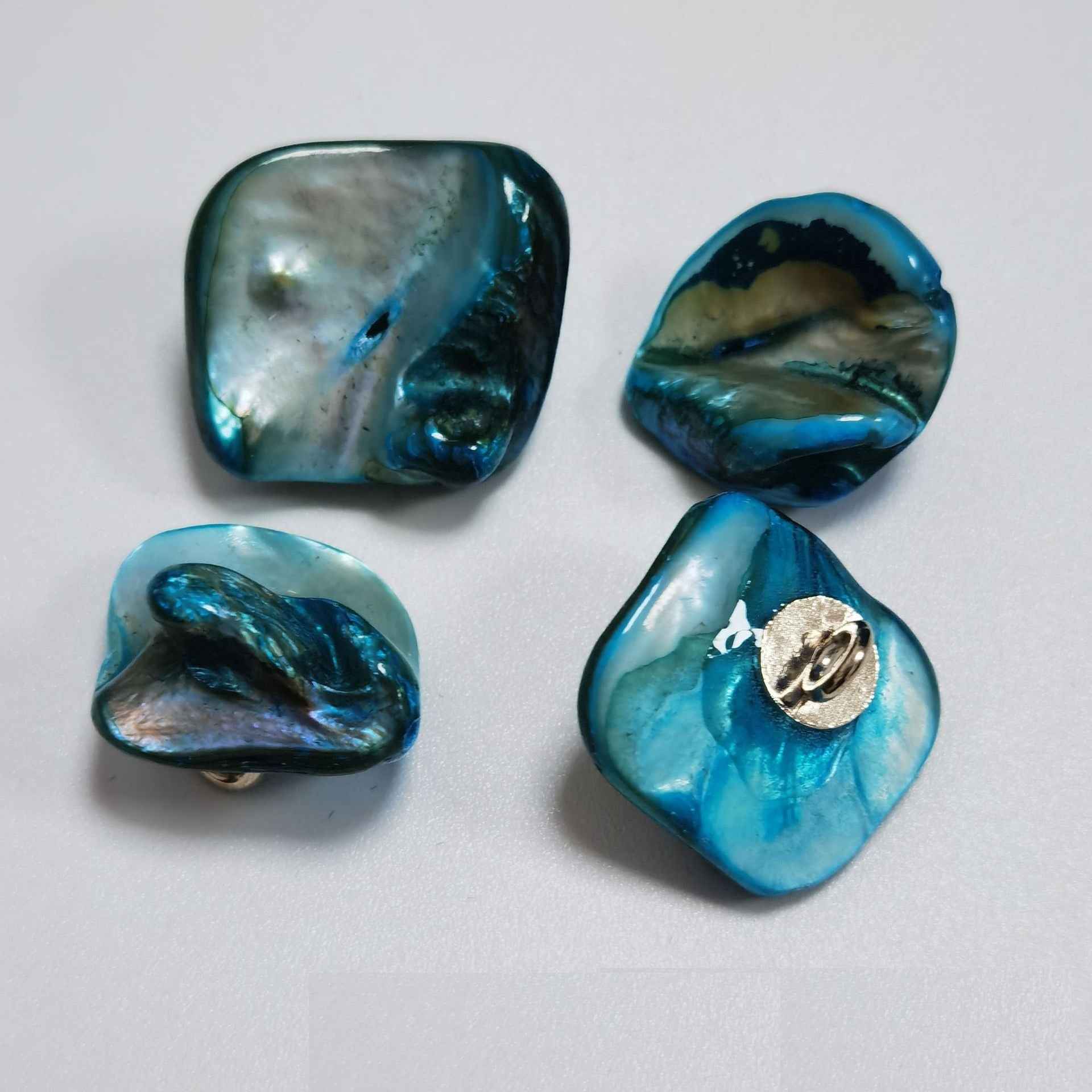 Teal-blue irregular shell shank buttons with metal loop shanks, glossy pearly.