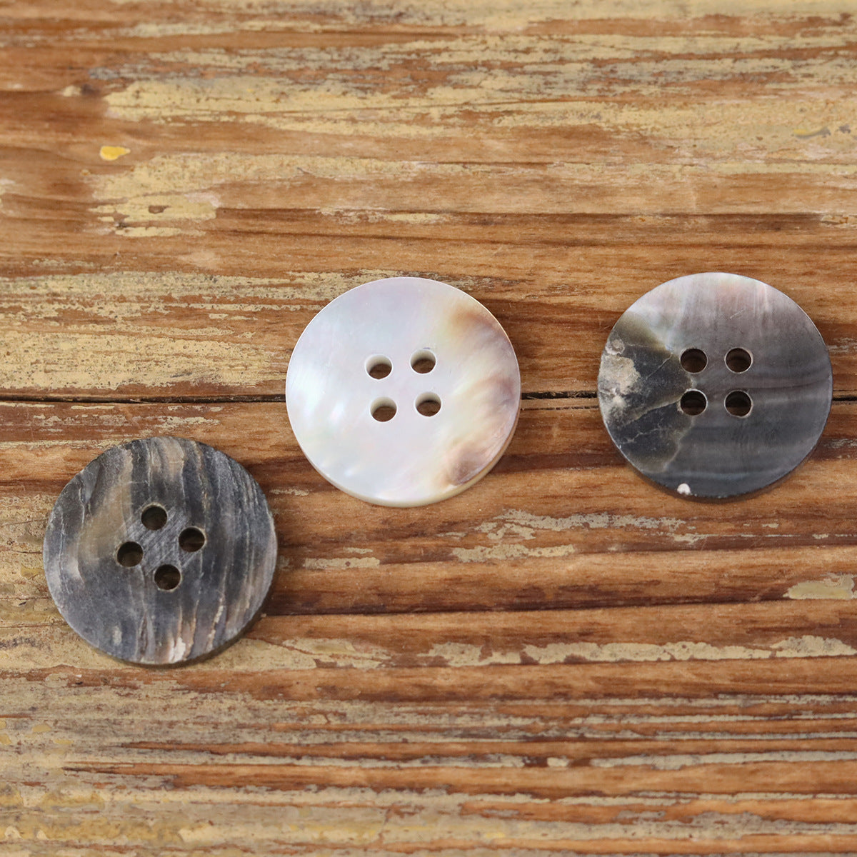Round 4-hole shell-style buttons, including dark grey, light pearl, and silver-grey tones