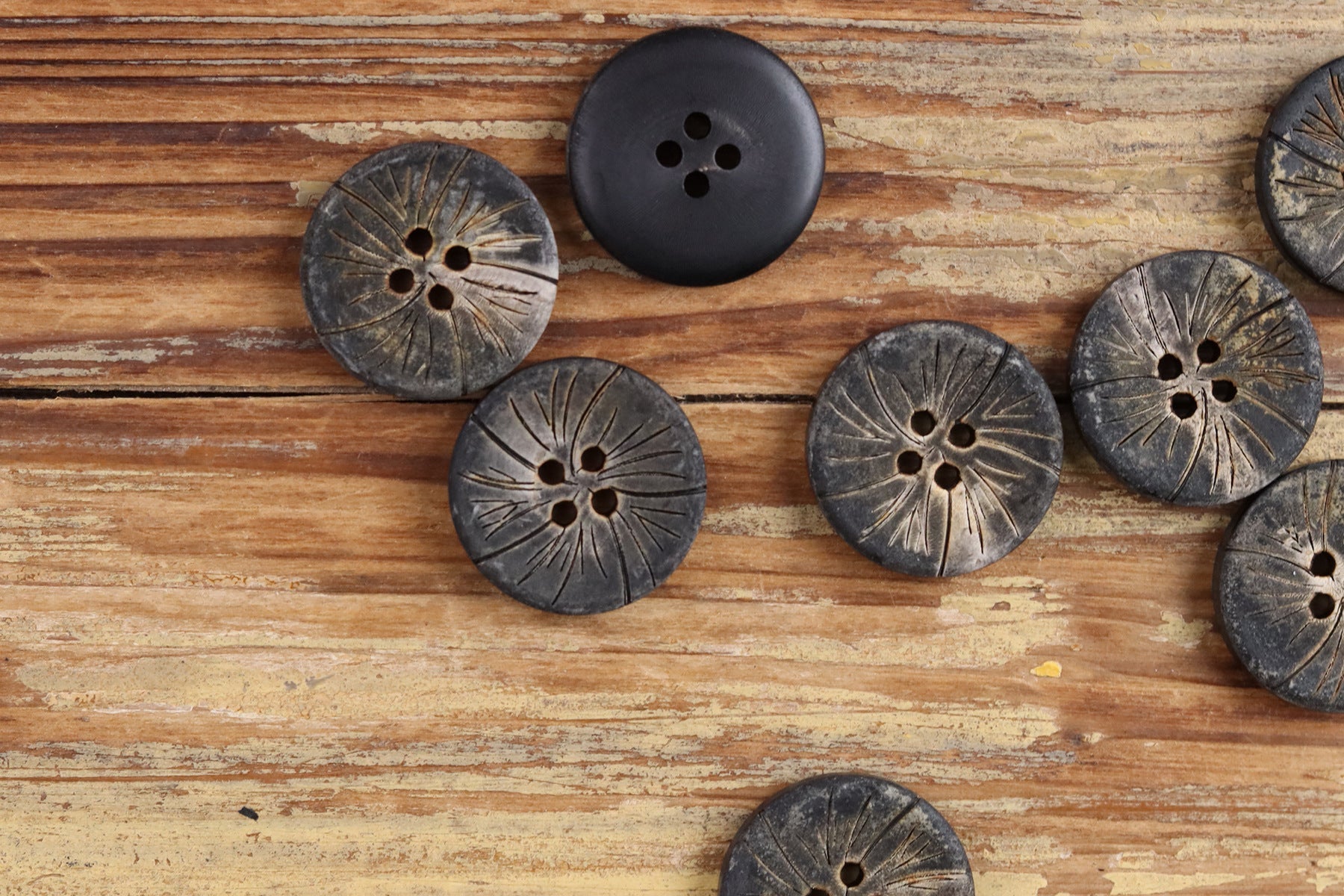 Dark round 4-hole buffalo horn buttons with carved radial texture