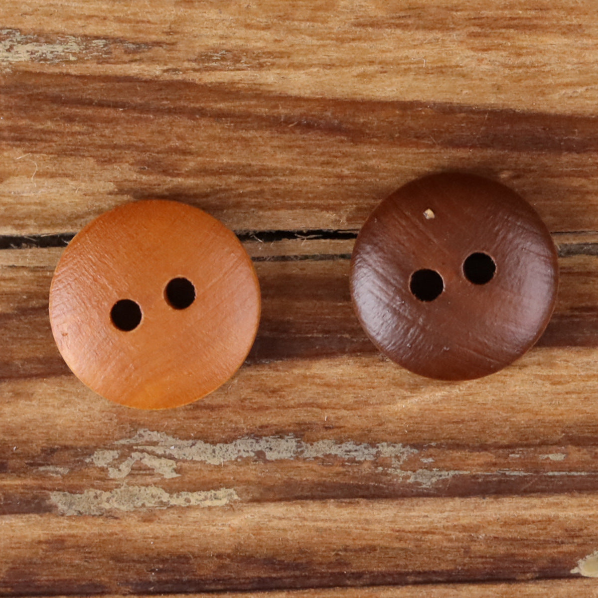 Two round 2-hole wood buttons, tan and dark brown.