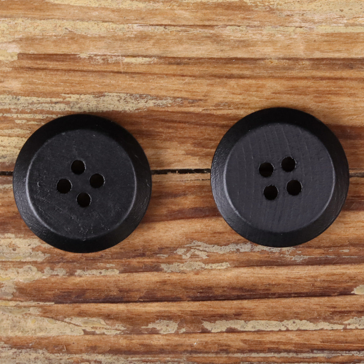 Pair of round 4-hole black buttons with smooth dark wooden face