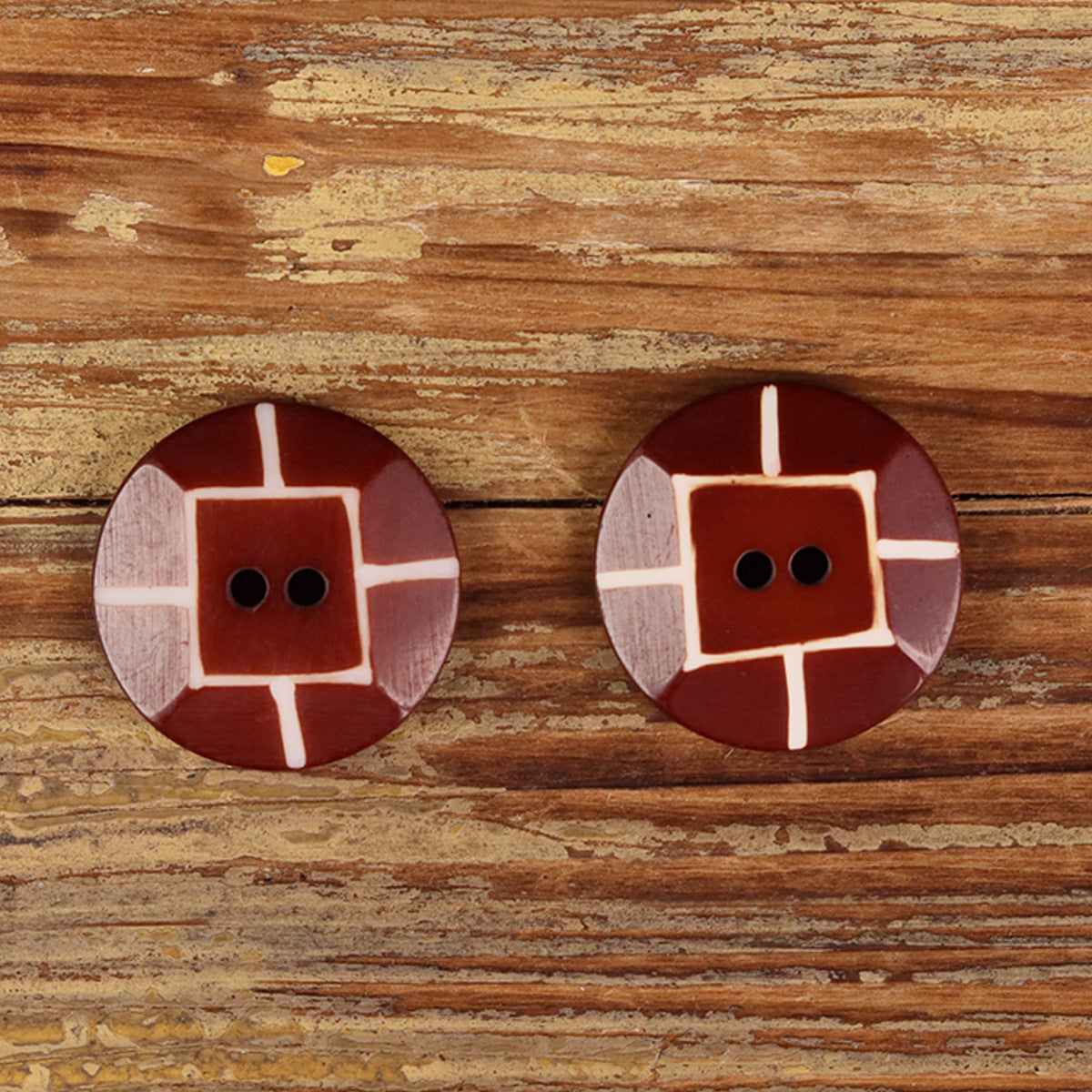 Two round red buffalo horn buttons with white cross inlay and 2 holes