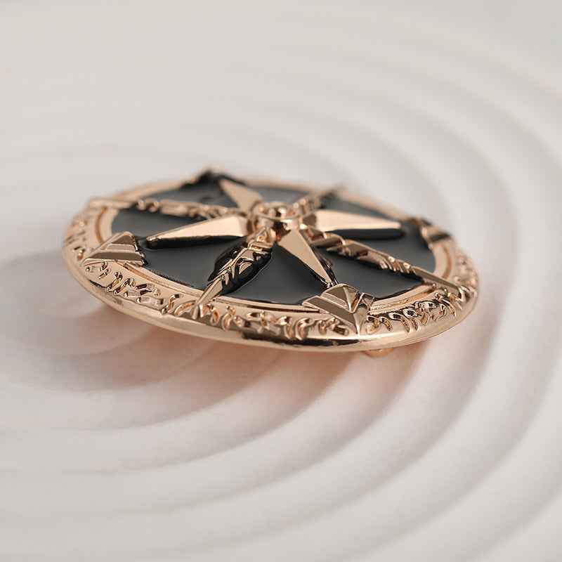 Gold-tone star brooch with black panels and eight-point metal rays, flat view
