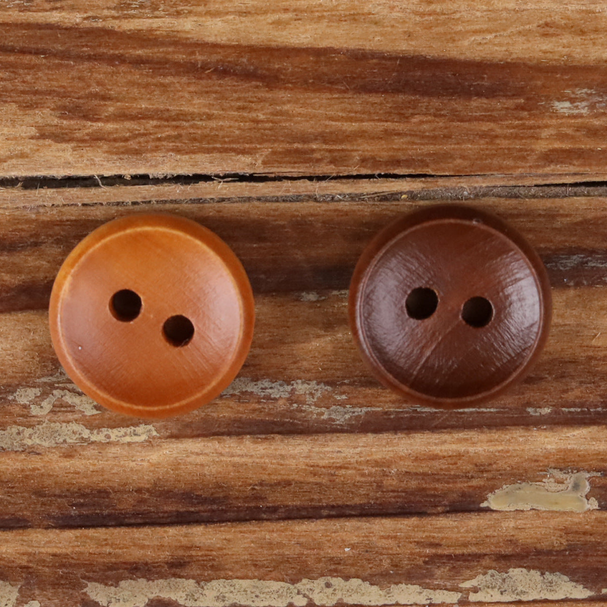 Two round 2-hole wood buttons, light orange and dark brown.