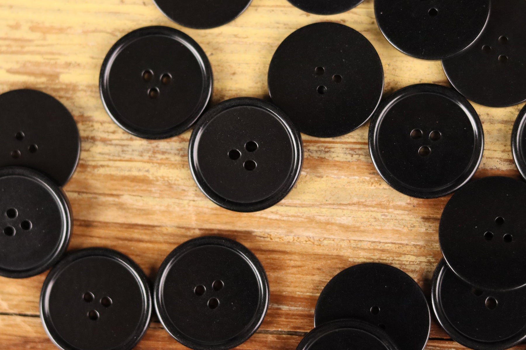 Assorted dark round 3-hole buttons with thin rim on wood background