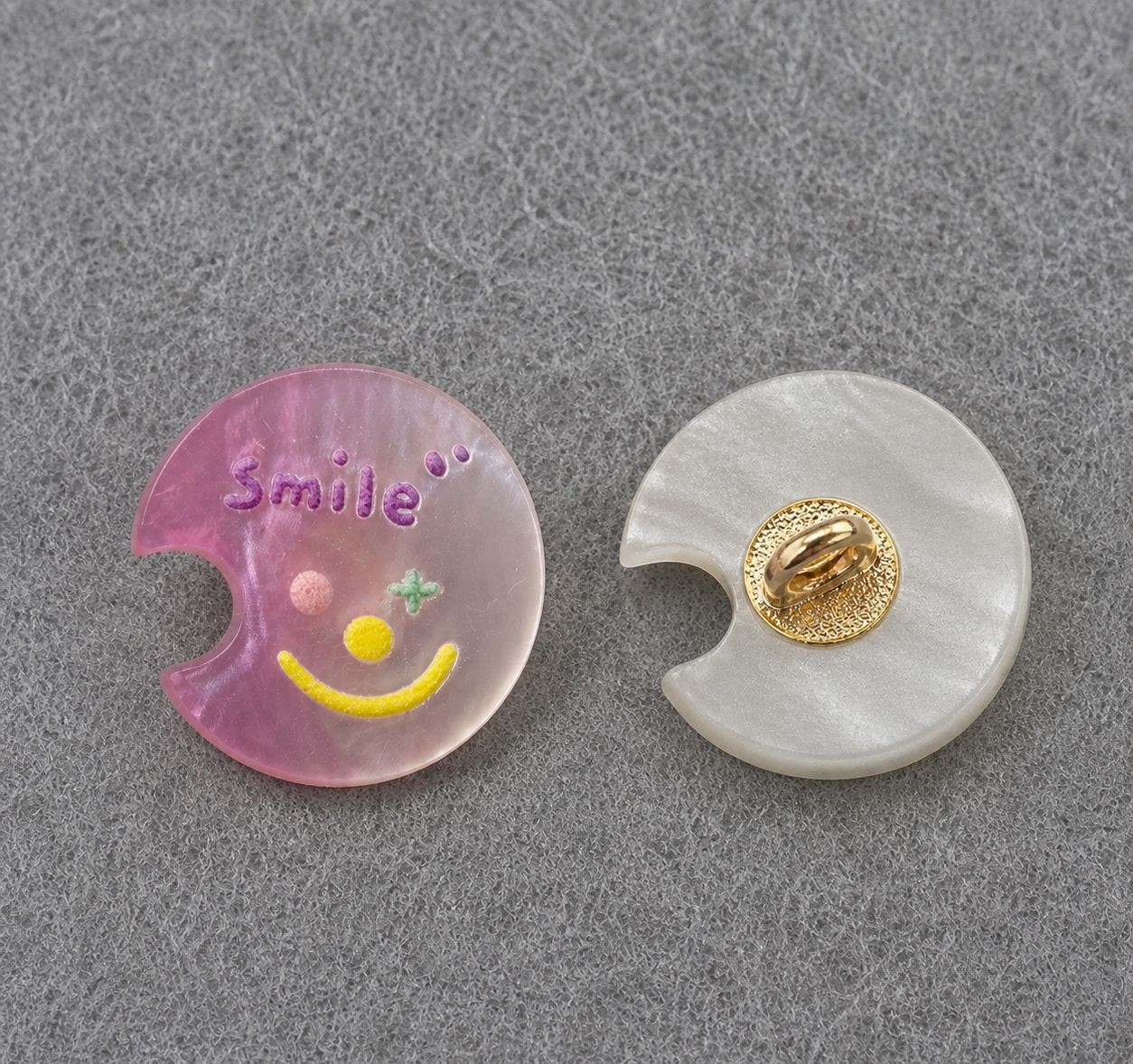 Pink moon-shaped resin shank button with colorful smiley face; gold back shank detail