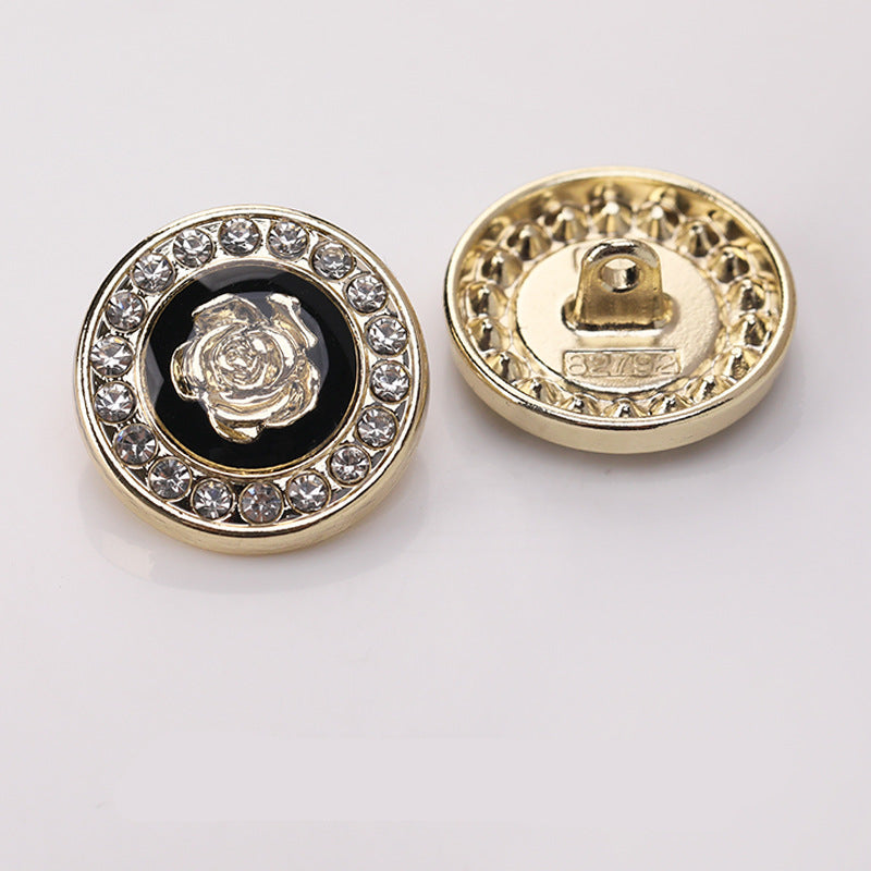 Runder Zierknopf mit goldfarbener Umrandung, Strasskranz und Blumenmotiv vor dunklem Einsatz