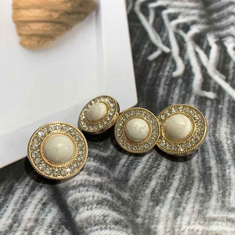 Round gold-tone button with rhinestone trim and light beige center, front view