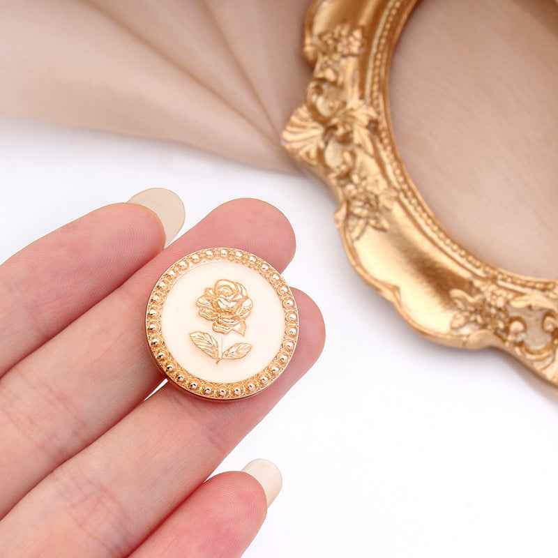 Round metal rose shank button, gold rim and white face with embossed rose