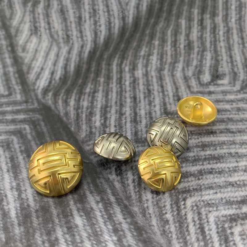 Gold and silver round mushroom-design buttons with geometric symbol embossing on face