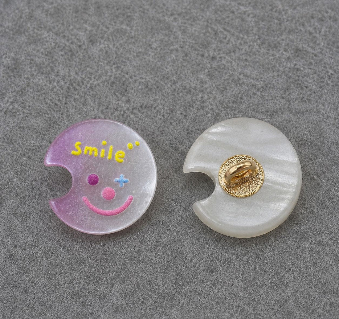 Pink moon-shaped resin shank button with colorful smiley face; gold back shank detail