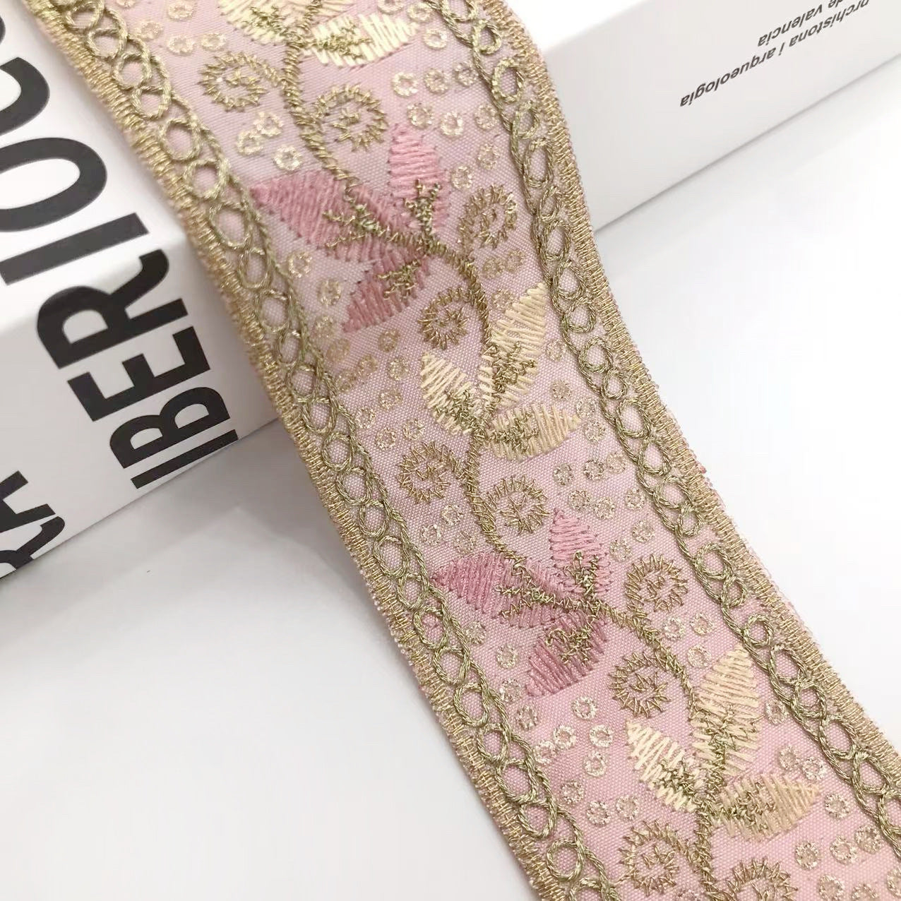 Goldene Stickborte mit pinkem Grund und feinen Blättermotiven, Kordelrand