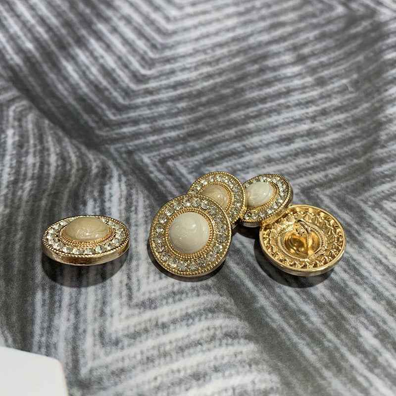 Round gold-tone buttons with rhinestone trim; one shows the back plate