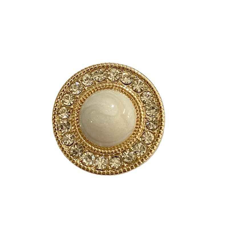 Close-up: gold-tone round button with clear rhinestones and light beige center