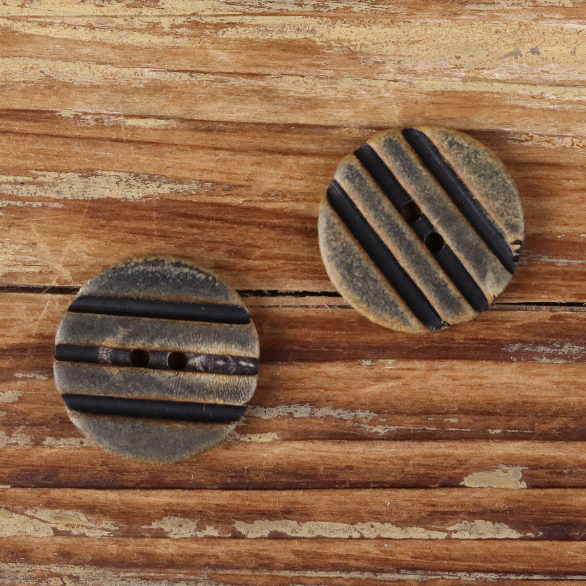 Grooved round horn-look button with two holes, black striped recessed channels
