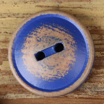 Round blue wood 2-hole button with two dark holes, close-up