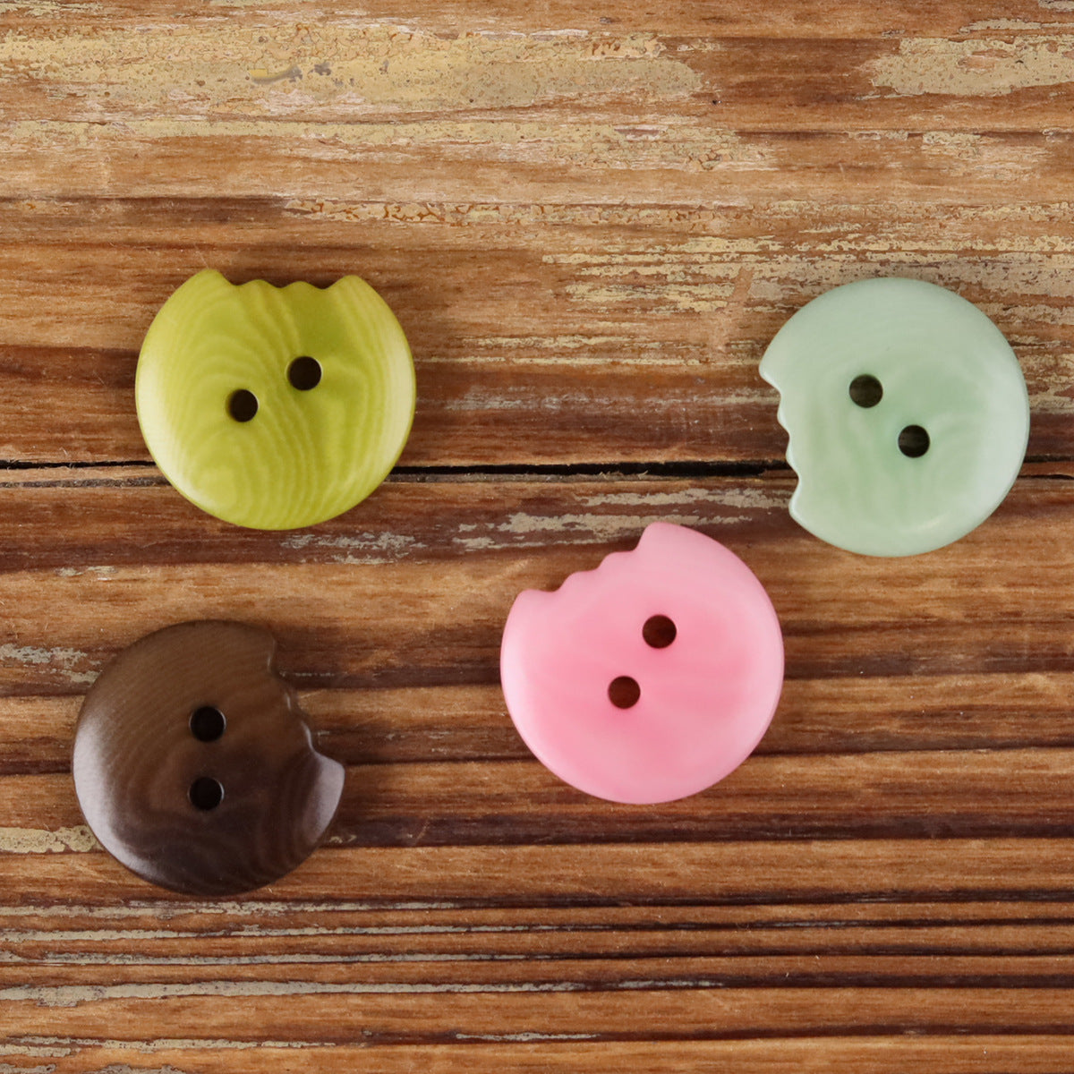 Set of irregular seed buttons in yellow, pale green, pink, and dark brown; two holes each.