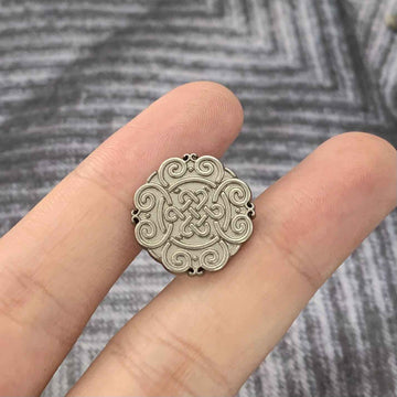 Matte silver Chinese knot motif metal button, round with raised swirl design.