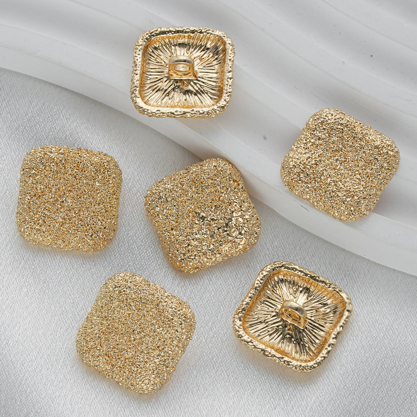 Square textured metal shank buttons in gold, with front and back views