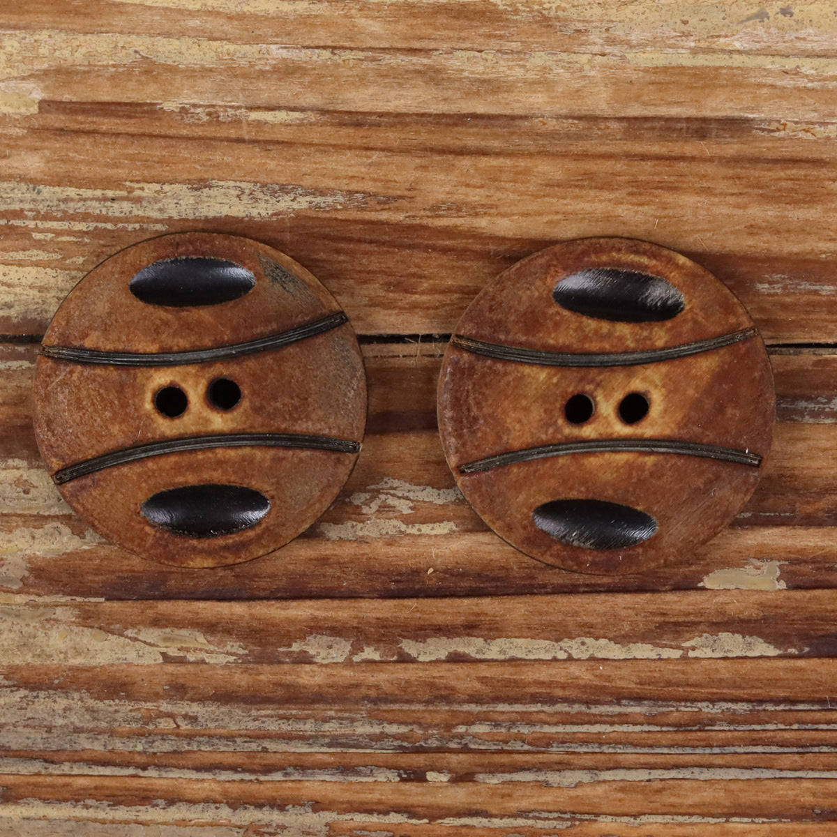 Handmade horn button pair, basketball texture with black oval face and two holes
