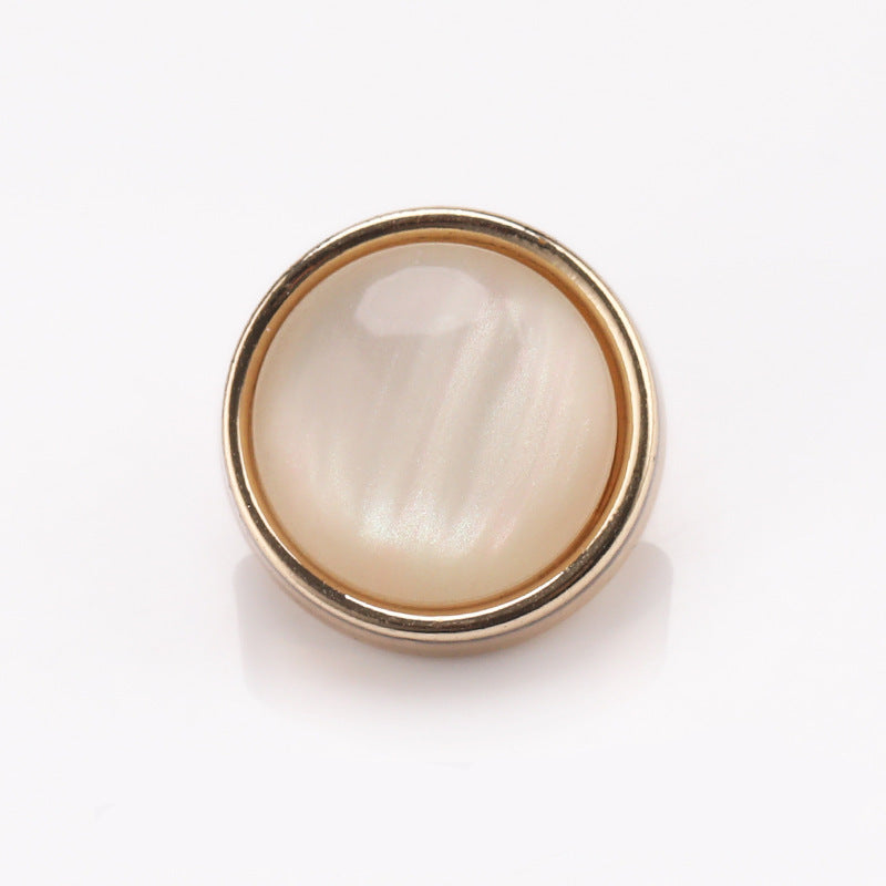 Cat-eye stone button with metal frame, shiny light gold rim and pearly white center