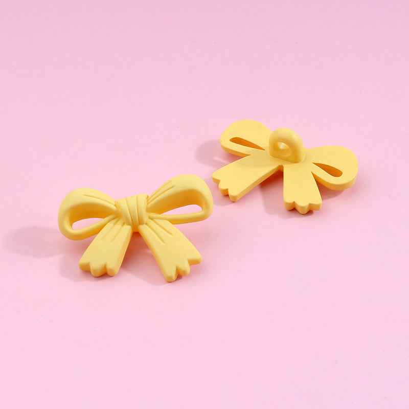 Yellow bow-shaped plastic shank buttons with loop shanks, 2-piece view
