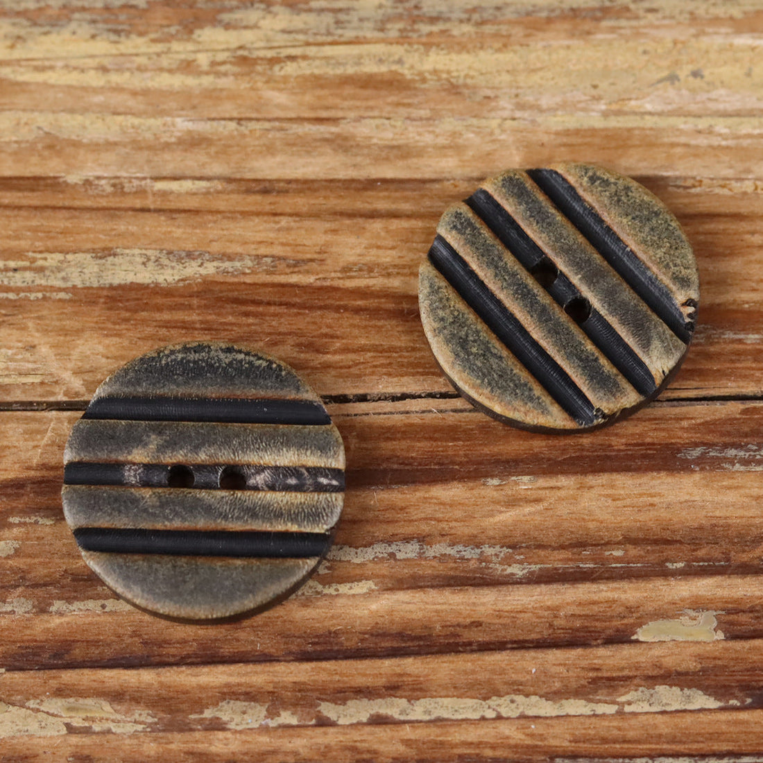 Grooved round horn-look button with two holes, dark striped band detail