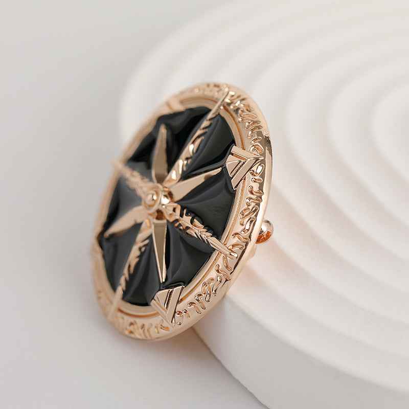 Rose-gold star brooch with black enamel center and ornate rim, angled view