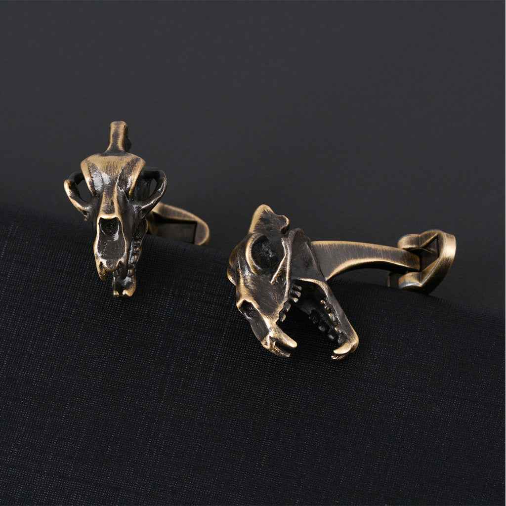 Pair of bronze dinosaur skull cufflinks, one front-facing, one side view