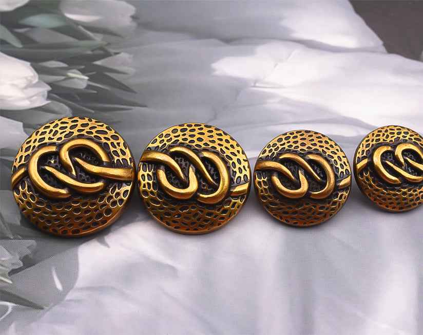 Set of round antique gold-tone metal shank buttons with dotted texture and swirl motif