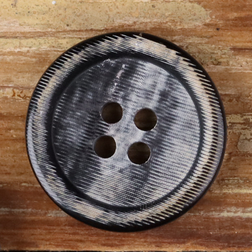 Close-up of a 4-hole round button with light speckled edge and four holes