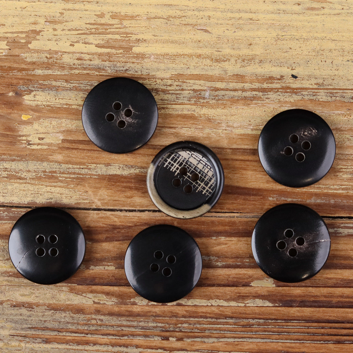 Set of 4-hole round buttons in dark tones, visible four-hole button faces