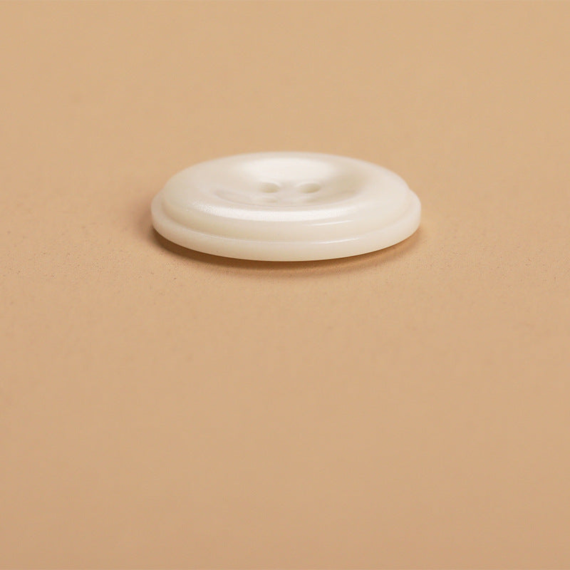 Single round 4-hole natural fruit shell button, off-white, side profile