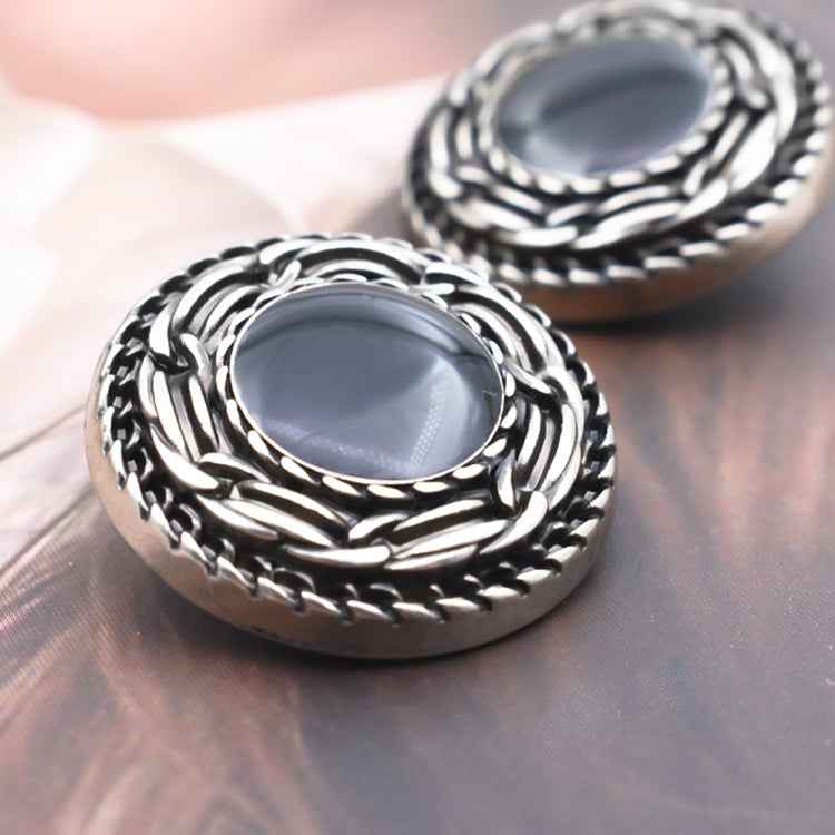 Close-up: black distressed metal shank button with braided edge, oval face, 18–25mm
