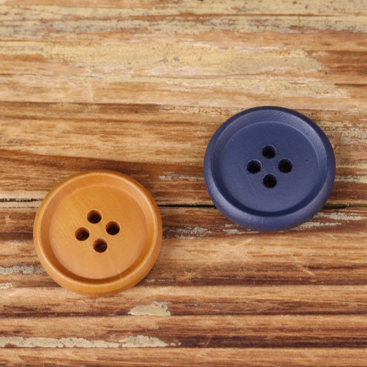 Brown and blue-purple round buttons with four holes on wood surface