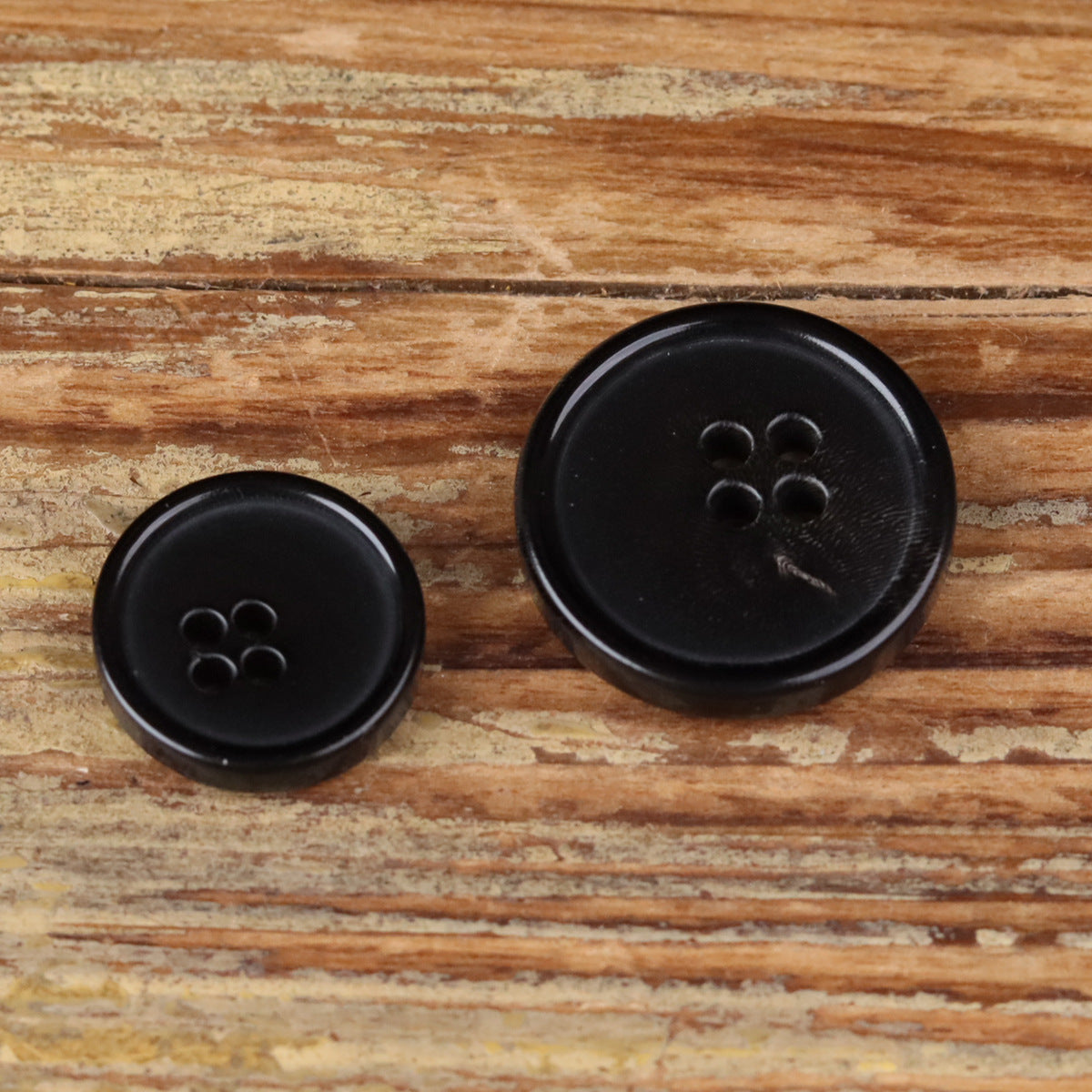 Set of two black 4-hole round buttons, front view